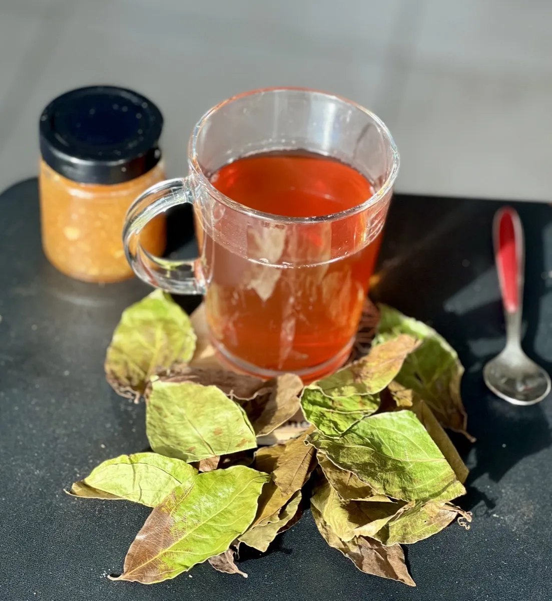 Rituel du matin : tasse de kinkeliba avec pot de miel pur et feuilles séchées